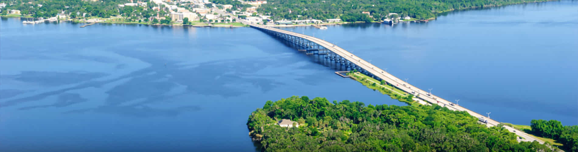 Aerial view of a bridge over bright blue water.